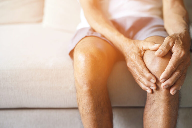 Older adult holding a sore knee before seeking knee pain relief in East Point, GA